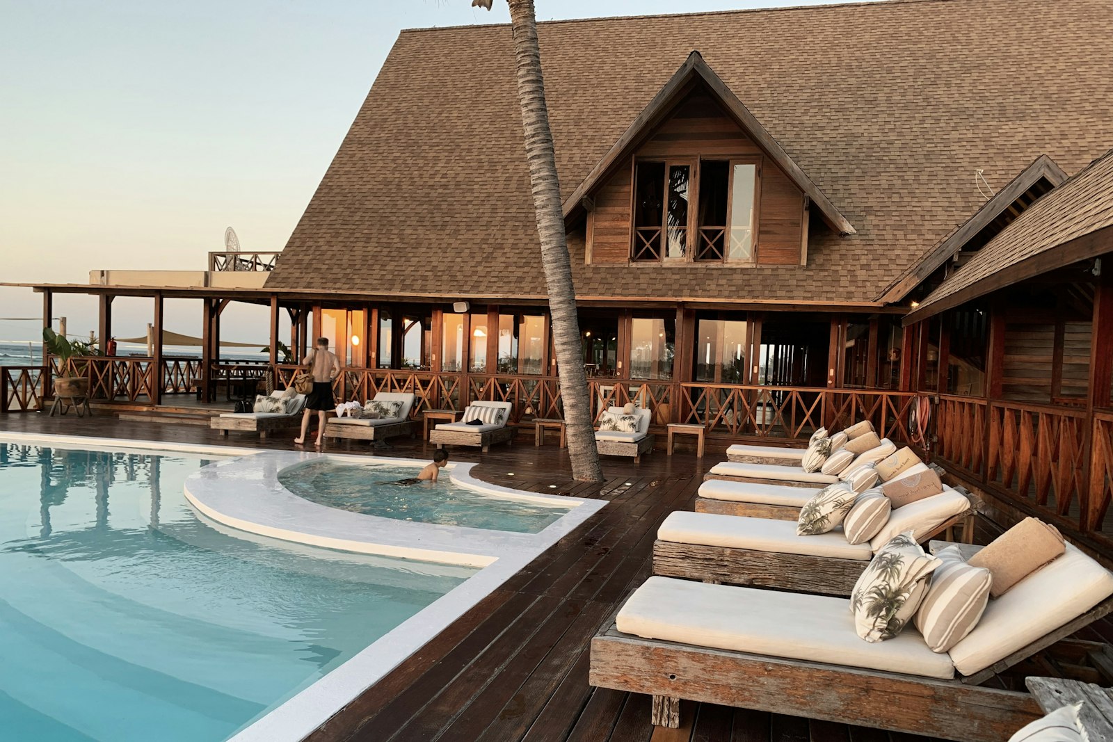 A resort-style pool deck with loungers in the evening