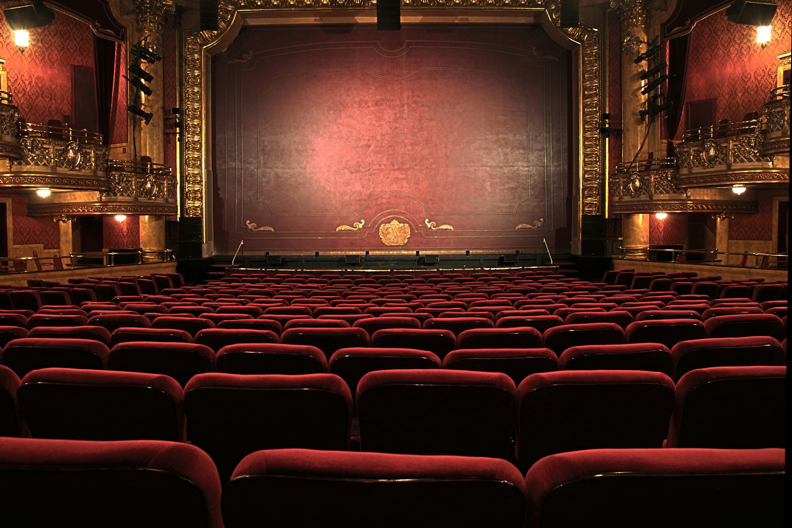 A historic theater auditorium with red velvet seats and curtain