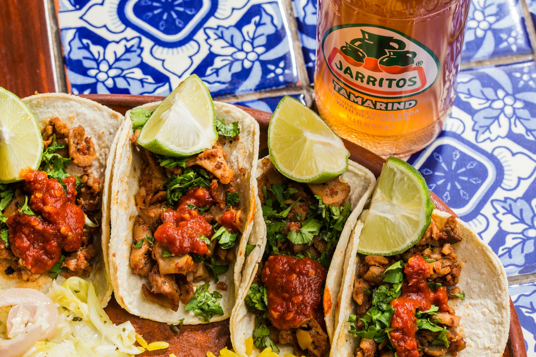 A platter of fresh street tacos with salsa, onion and cilantro